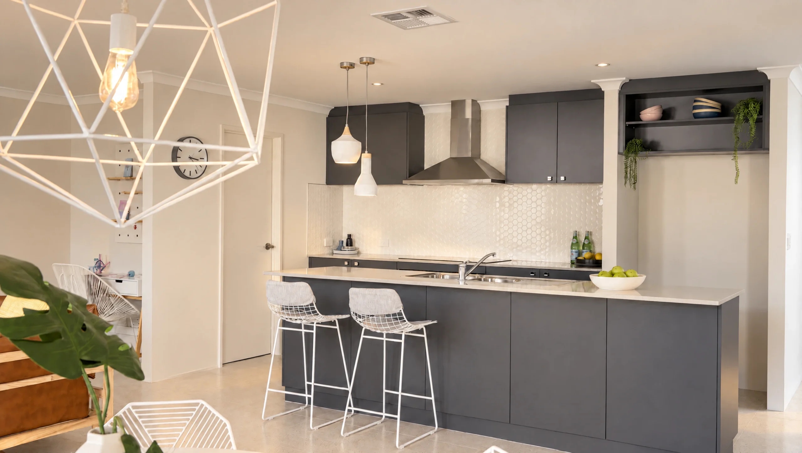 Modern dark grey kitchen with white hexagon backsplash and island with bar stools.