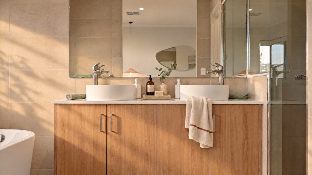 Modern ensuite bathroom with double vanity, wooden cabinets, and a glass shower.