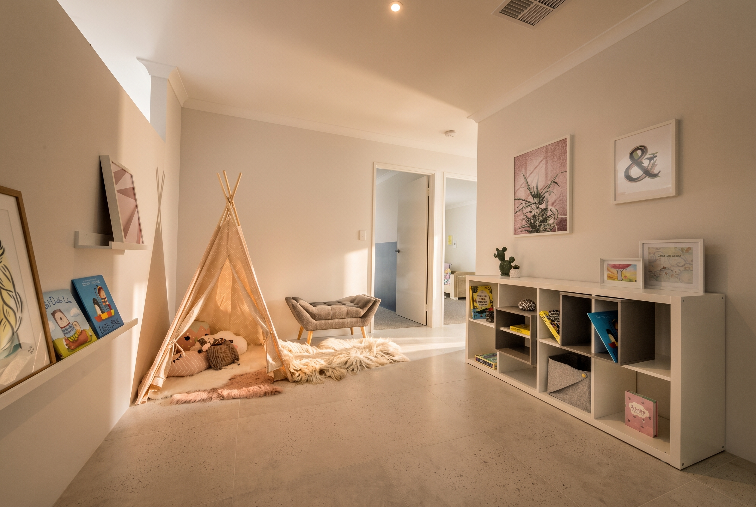 A child's play area with a teepee, books, and a shelf filled with toys and decor.