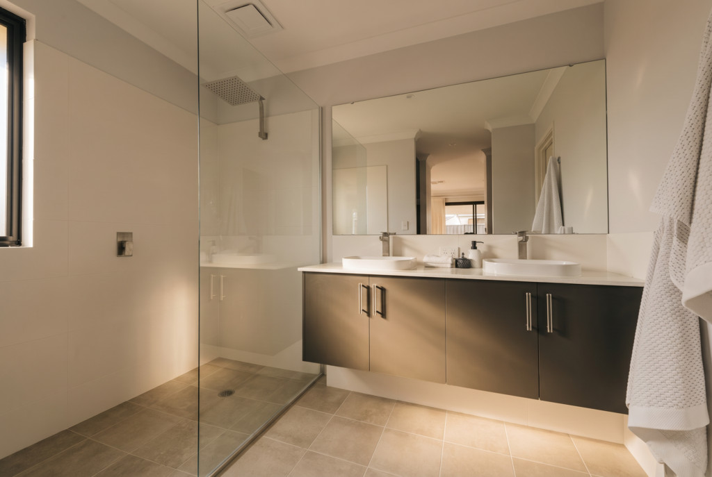 Modern double vanity bathroom with a walk-in shower and large mirror.
