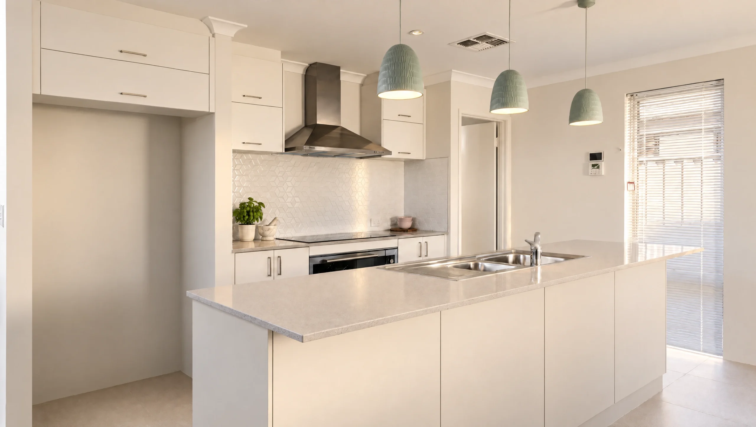 Modern white kitchen with island, stainless steel appliances, and pendant lights.