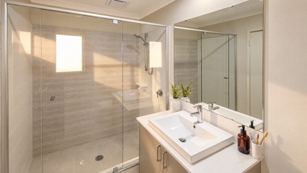 Modern bathroom with a glass-enclosed shower and a vanity with a white sink and chrome faucet.