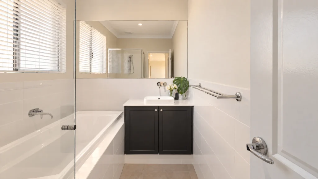 Modern bathroom with a white bathtub, dark vanity, and large mirror reflecting a shower.