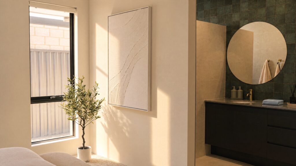 Modern bathroom vanity with a round mirror and gold fixtures, next to a window with a potted plant.