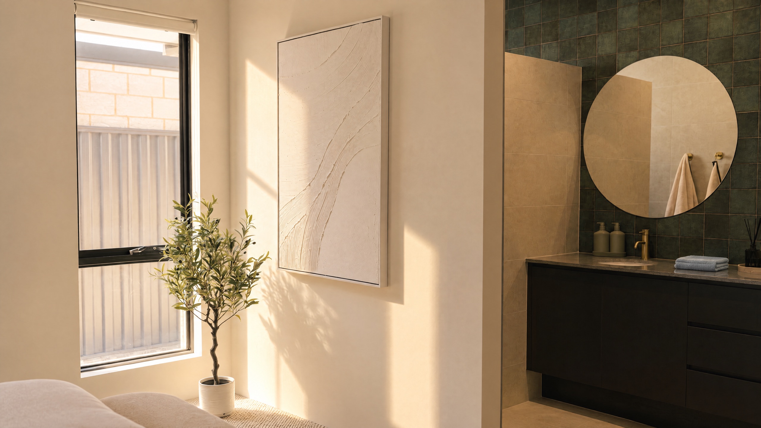 Modern bathroom vanity with a round mirror and gold fixtures, next to a window with a potted plant.