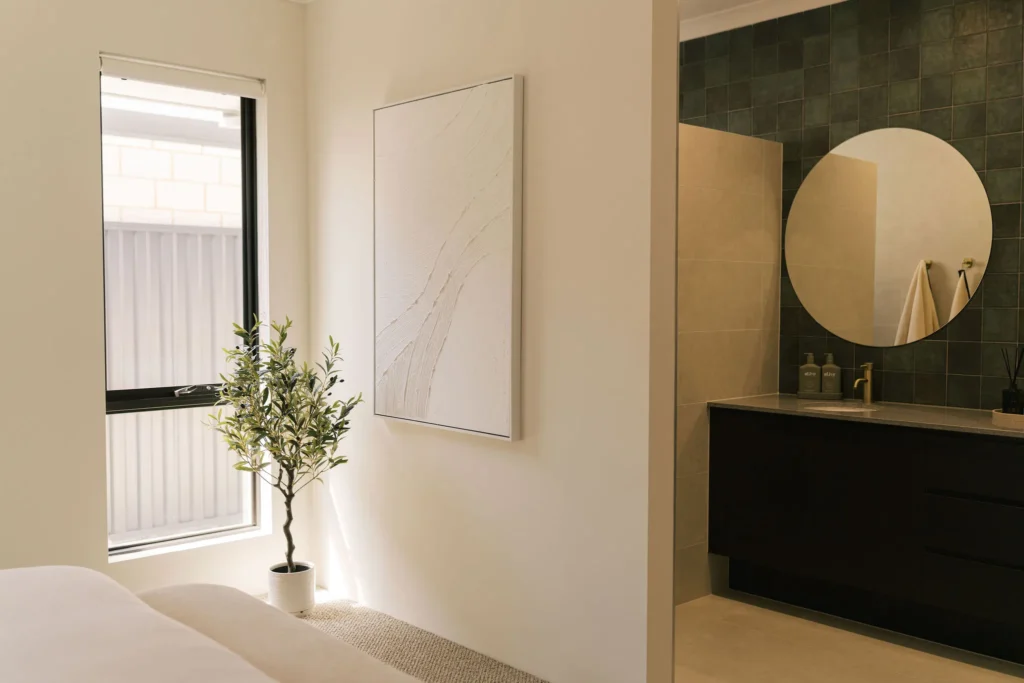 A modern bedroom with a large window and a vanity area with a round mirror.