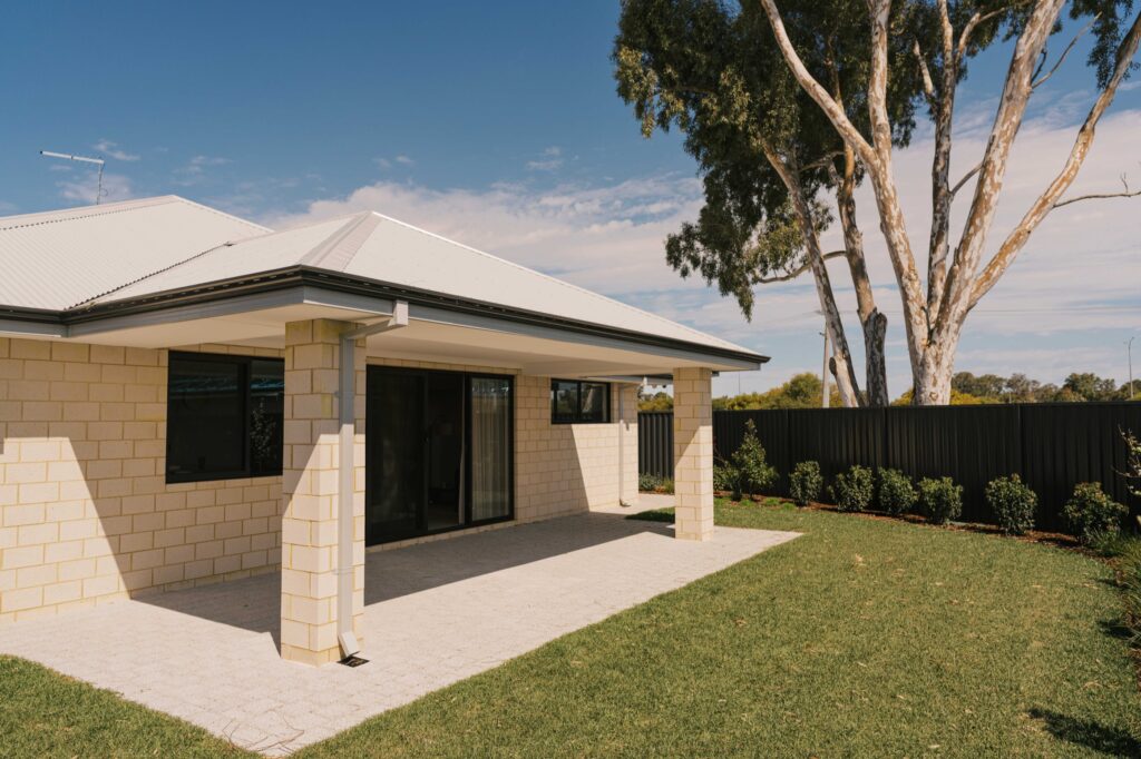 New Homes WA patio and backyard with light brick exterior and a large gum tree.
