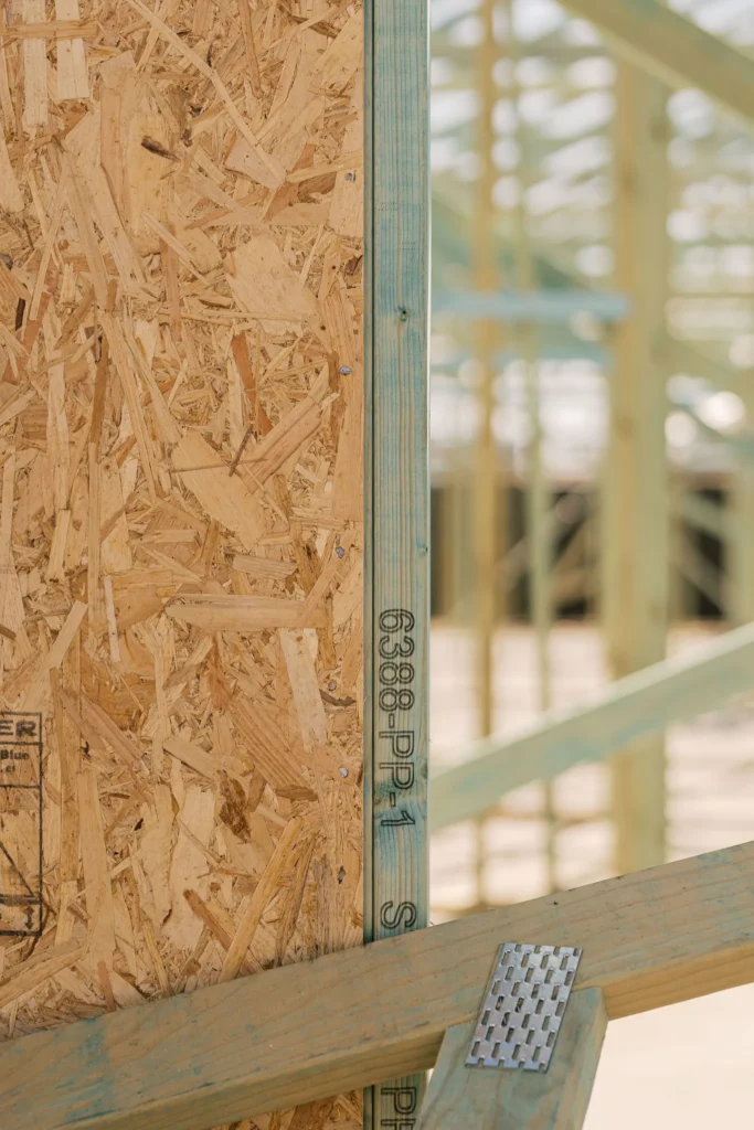 Close-up of oriented strand board and a green-treated timber frame with markings.