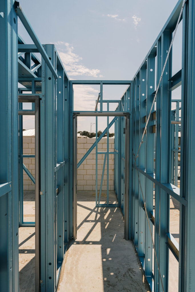 Blue steel framing for a new home under construction, showing doorways and wall studs.