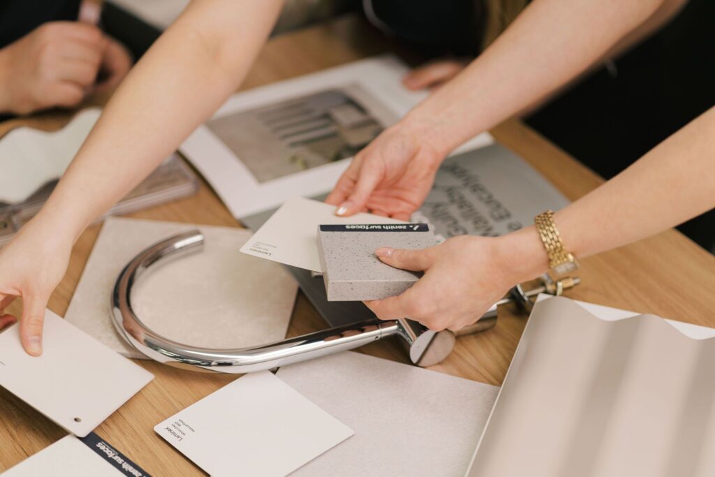 Hands select material samples and a faucet for a new home design.