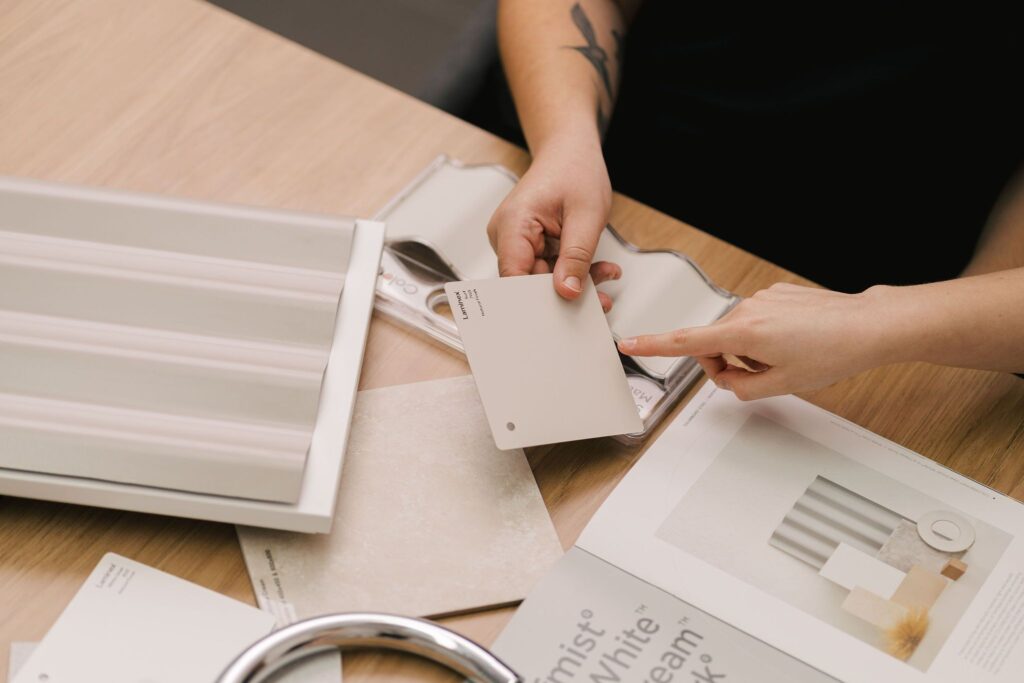Hands holding Laminex color swatches and material samples on a wooden table.