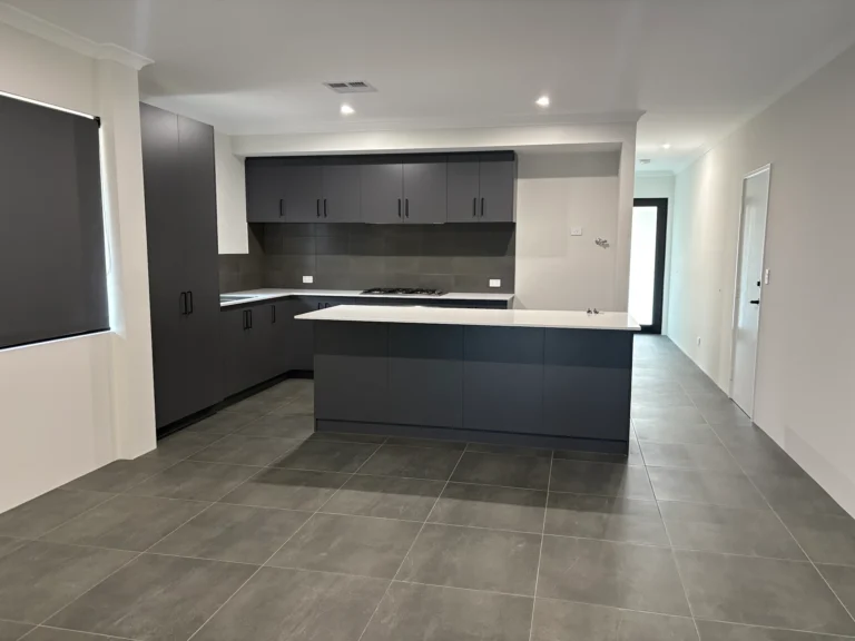 Modern dark grey kitchen with island and white countertops, tiled floor.