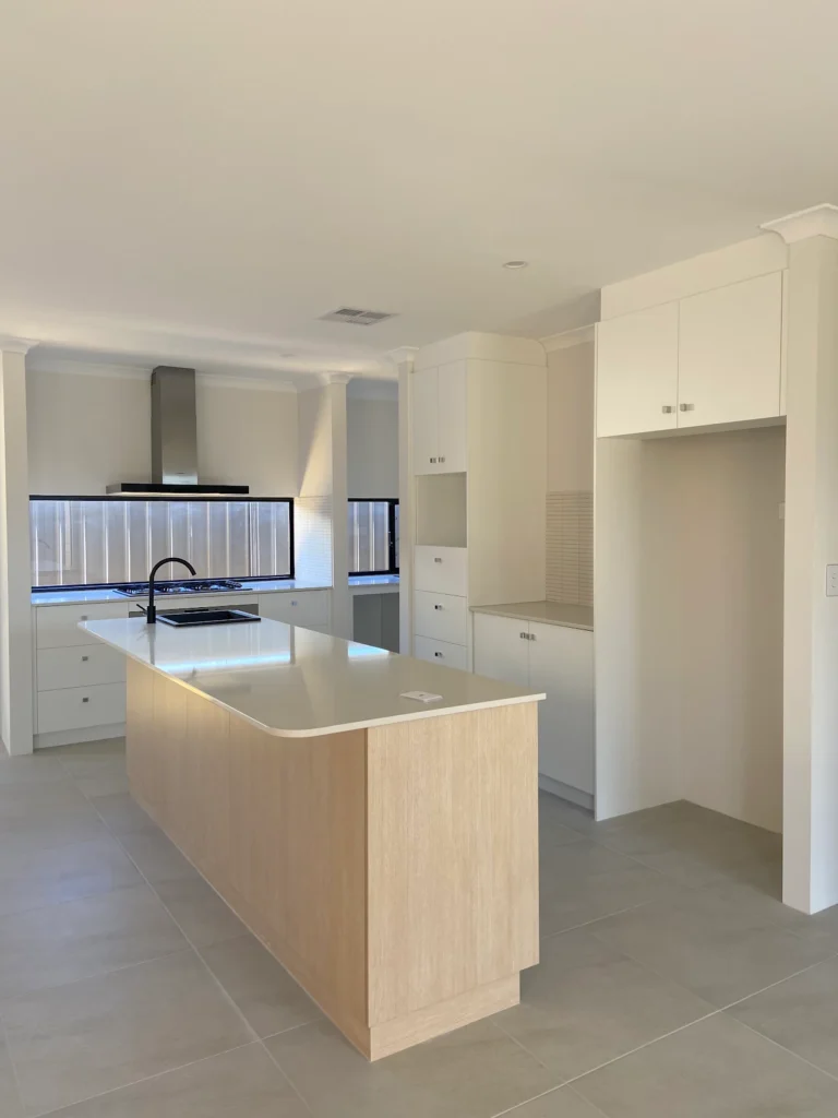Modern kitchen with a large island, white cabinetry, and a sleek range hood.